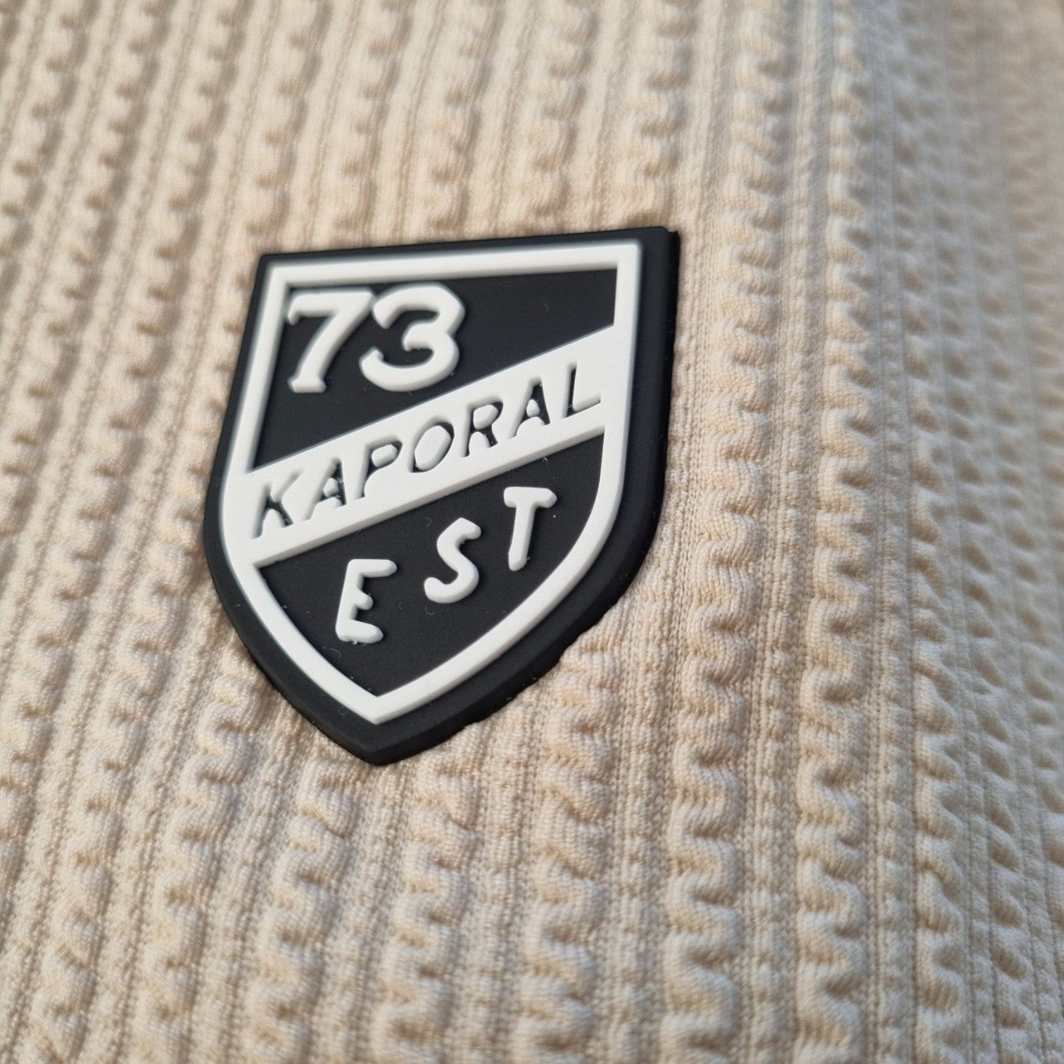 Klothco Kaporal beige textured fabric with a black and white shield logo patch featuring 73 EST branding.
