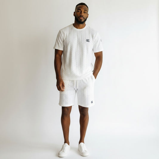 A man wearing a white Klothco cable-knit short sleeve shirt and matching shorts set with a drawstring waist.