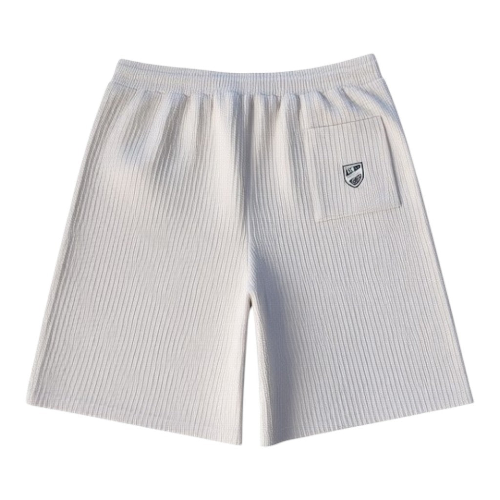 Klothco white textured ribbed shorts with an elasticated waistband and a small shield logo patch on the back pocket.
